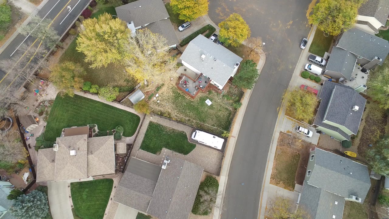 Overhead view of houses, lawns, trees, and a residential street.