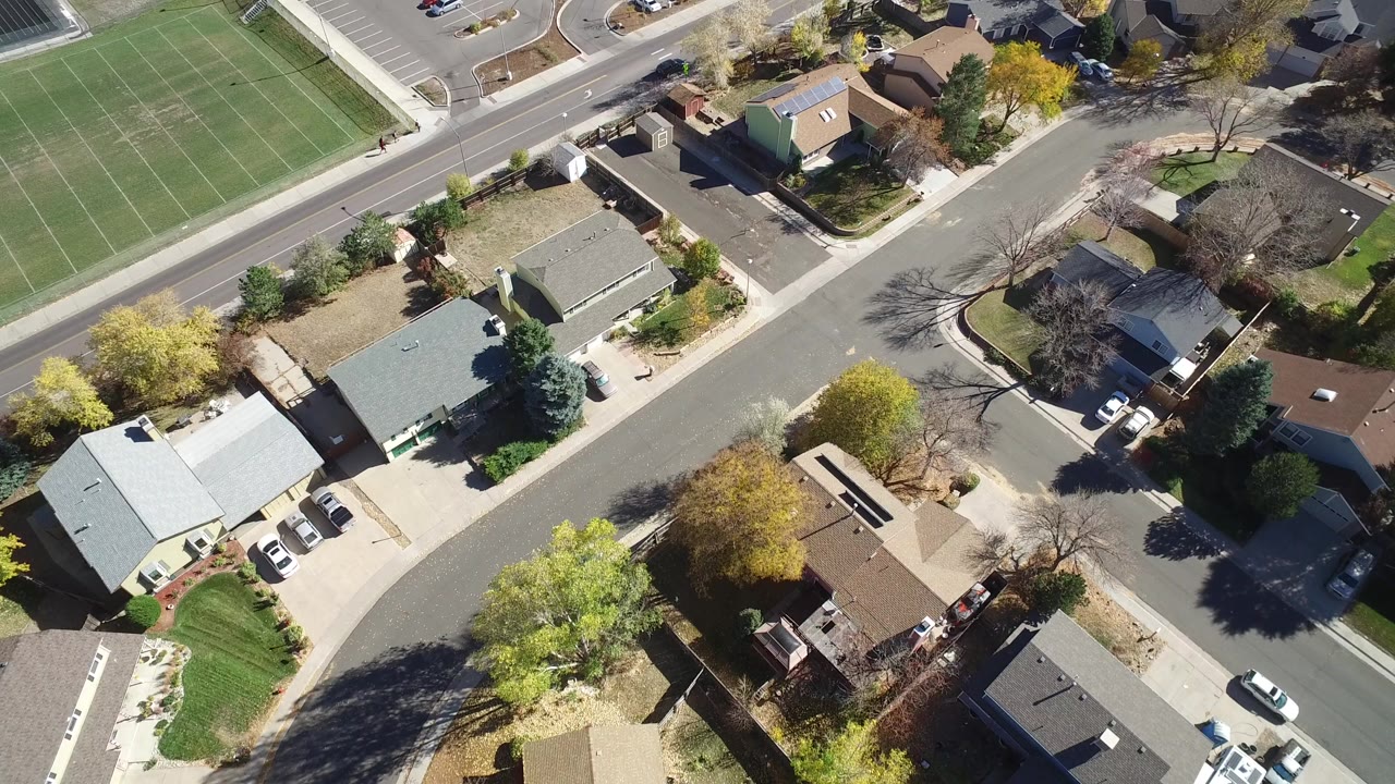 Aerial view of homes, curving streets, and a green sports field.