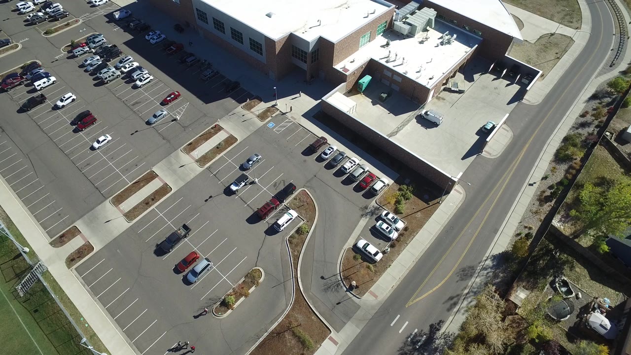 High-angle parking lot view with cars, building entrance areas, and landscaped edges.