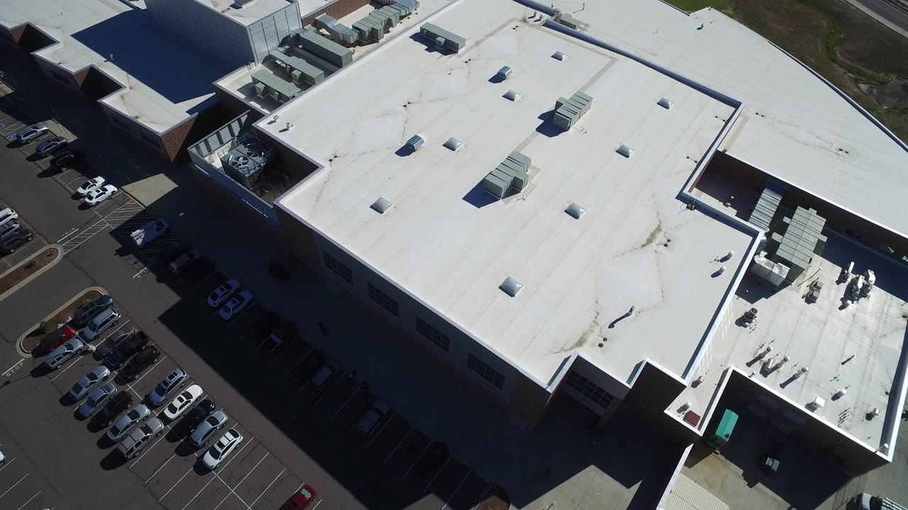 Drone-like aerial angle over a commercial building roof and parking area