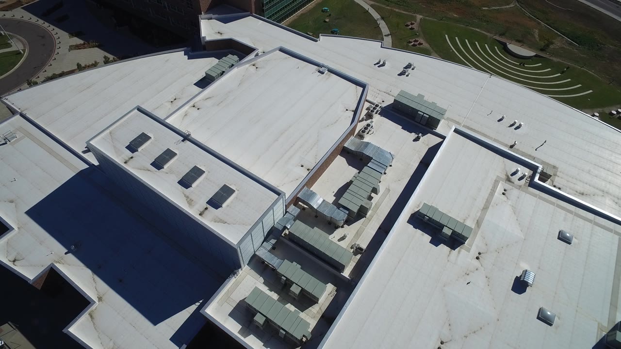 Top-down view of angular white roofs beside landscaped paths.