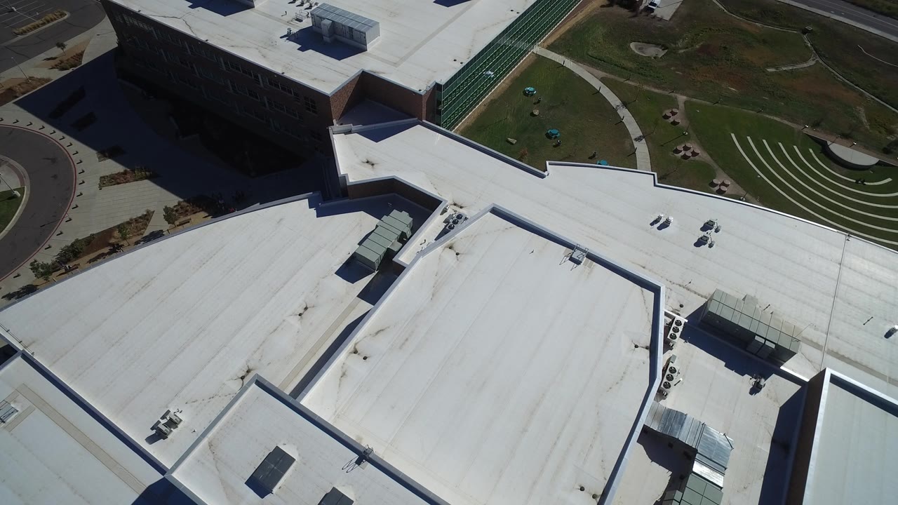 Aerial composition of rooftop sections and adjacent green grounds.