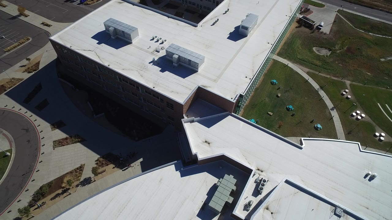 Aerial view of office rooftops, lawn, walkways, and nearby parking.