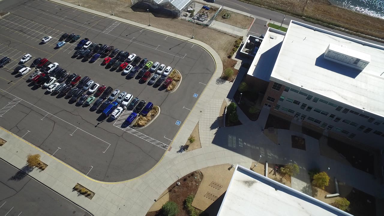 Aerial view of a business parking lot beside a white-roofed building.