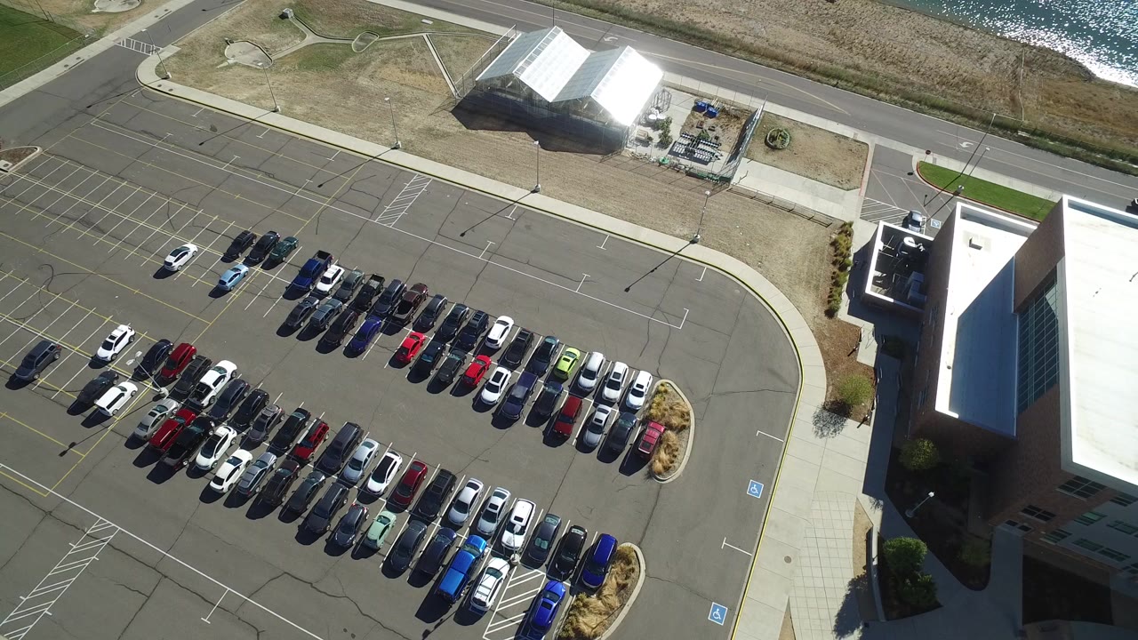 Aerial view of a parking lot beside buildings, road, and water