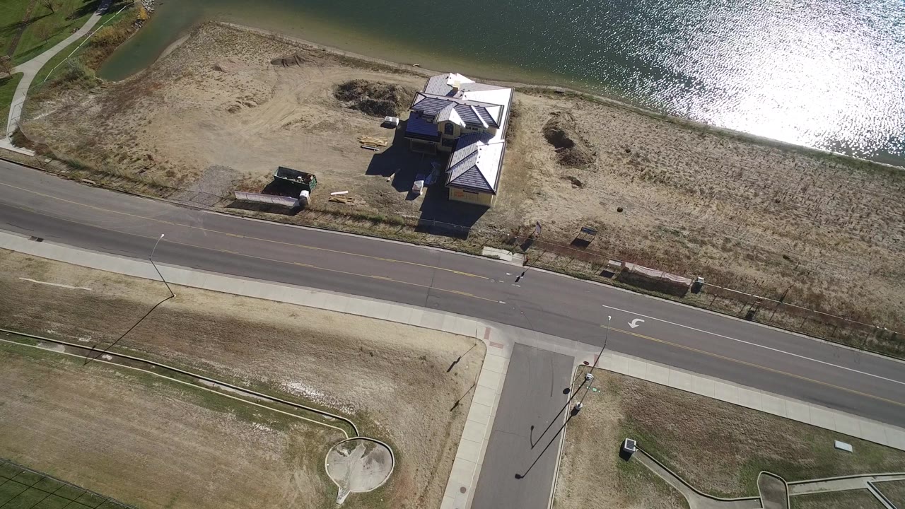 Drone-like aerial frame of a house by a lake and a quiet road.