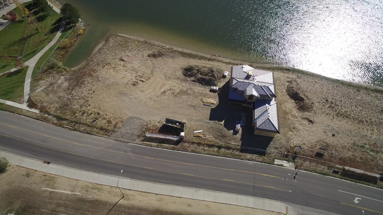 High aerial view of home beside lake and curved roadside