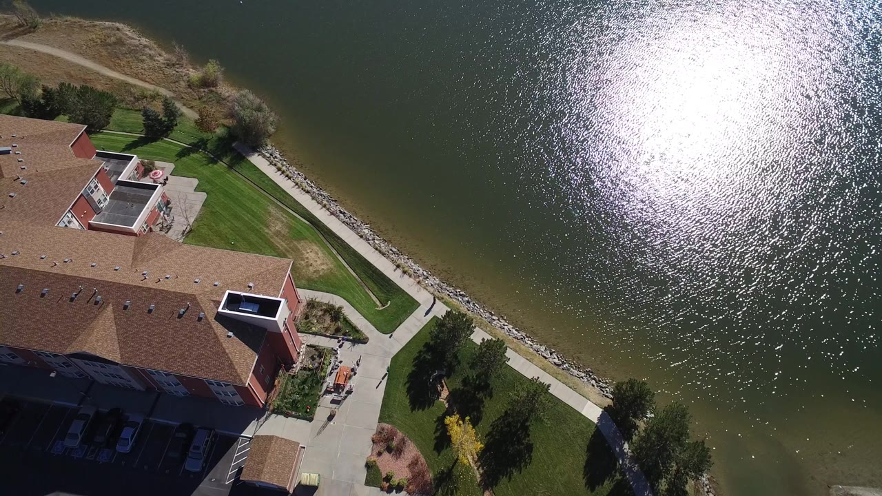 Top-down view of a large building beside a landscaped lake edge.