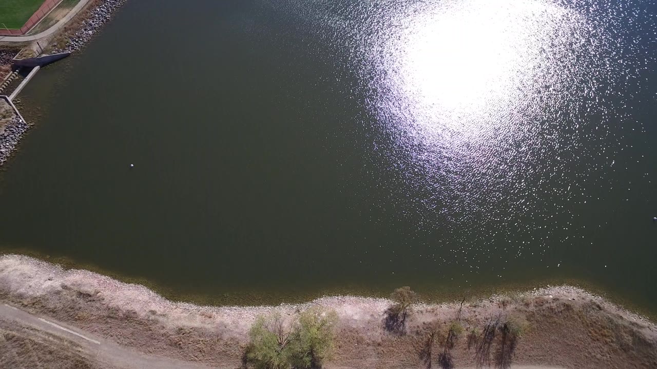 Top-down lake view with bright reflection and beach strip
