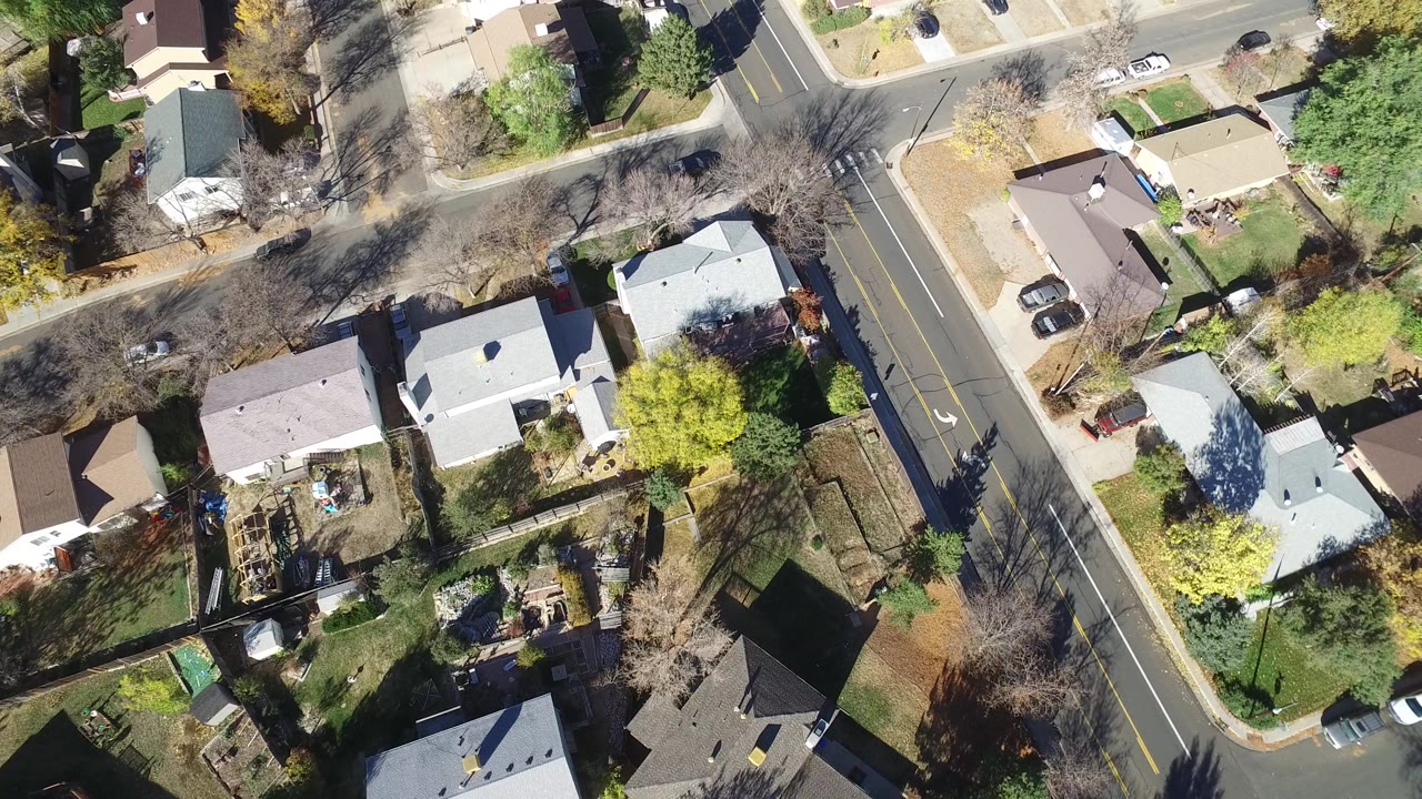 Aerial frame over Hidden Lake, Colorado showing pale rooftops, fenced yards, driveways, autumn trees, and a residential road, with no visible people.