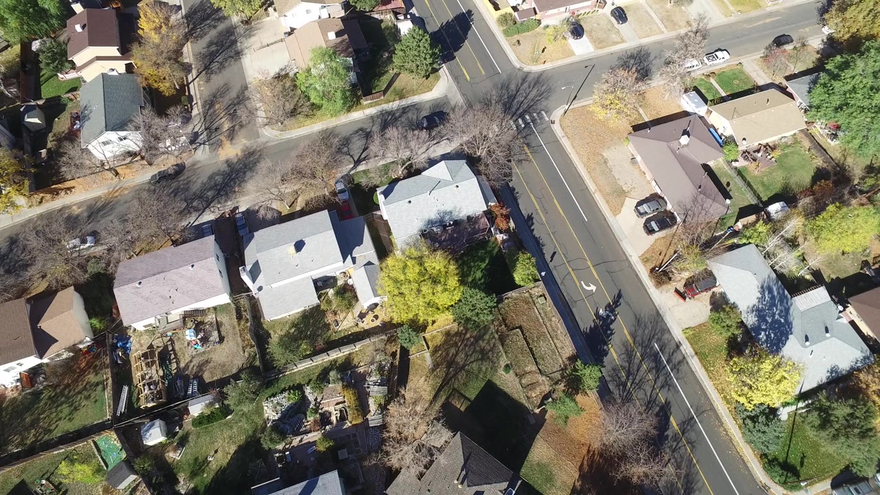 Top-down neighborhood view with houses, road lanes, and parked vehicles.