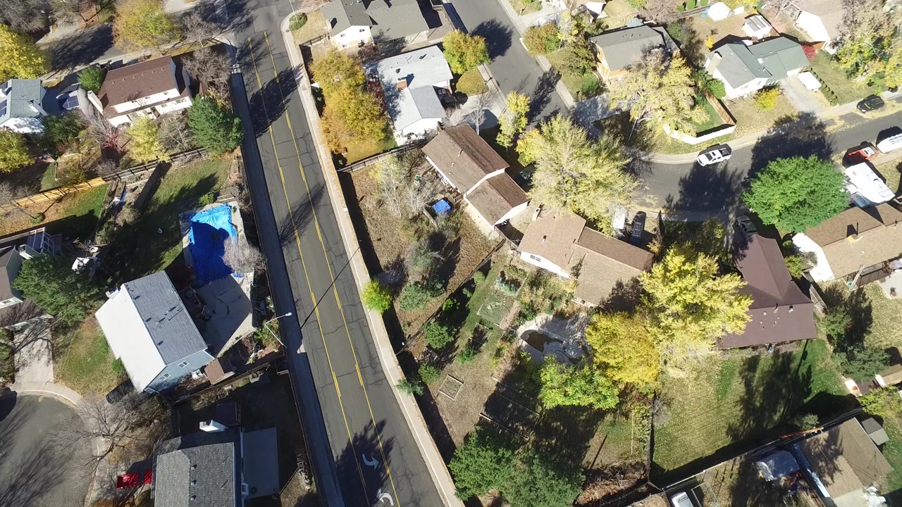 Aerial view of homes, trees, and a road beside a residential block.