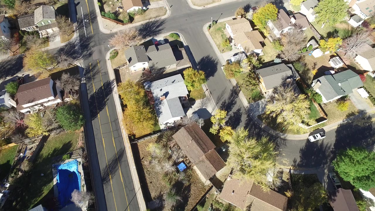 Top-down aerial view of houses, trees, and a residential intersection.