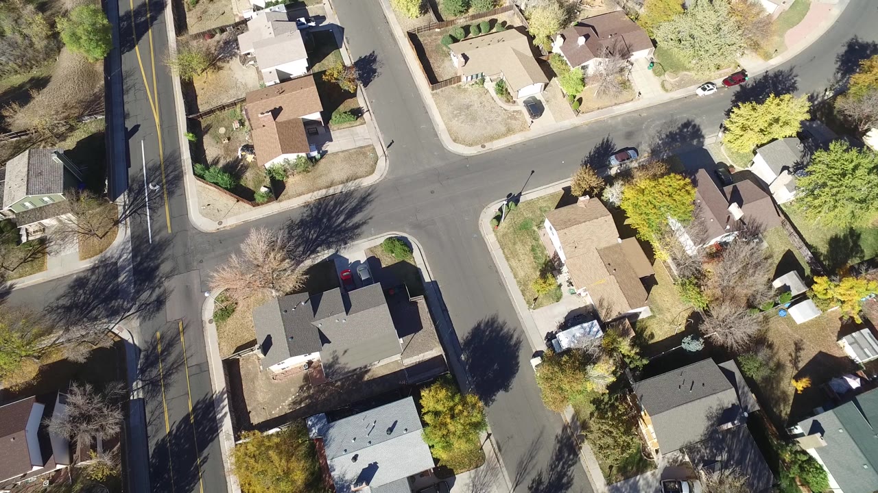 Top-down neighborhood view with a main road at left and homes to the right.