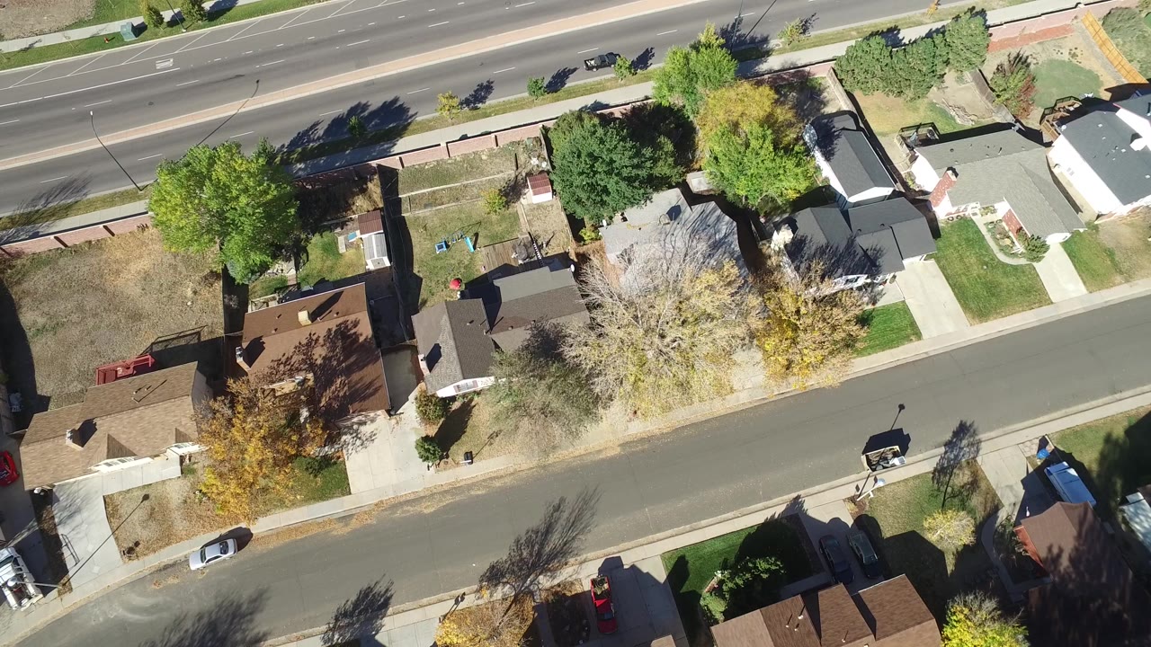 Top-down neighborhood block with homes, trees, and a road above.