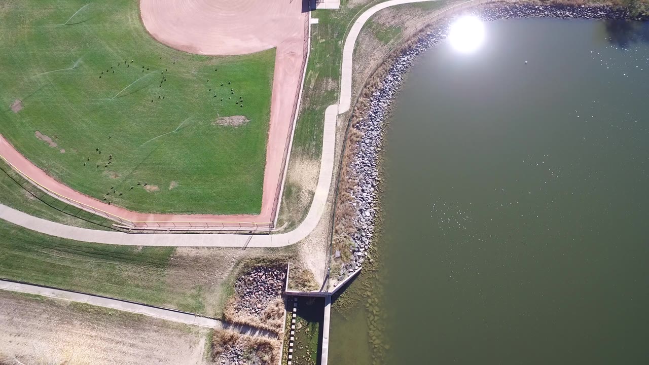 Overhead view of a baseball field beside a lake shoreline.