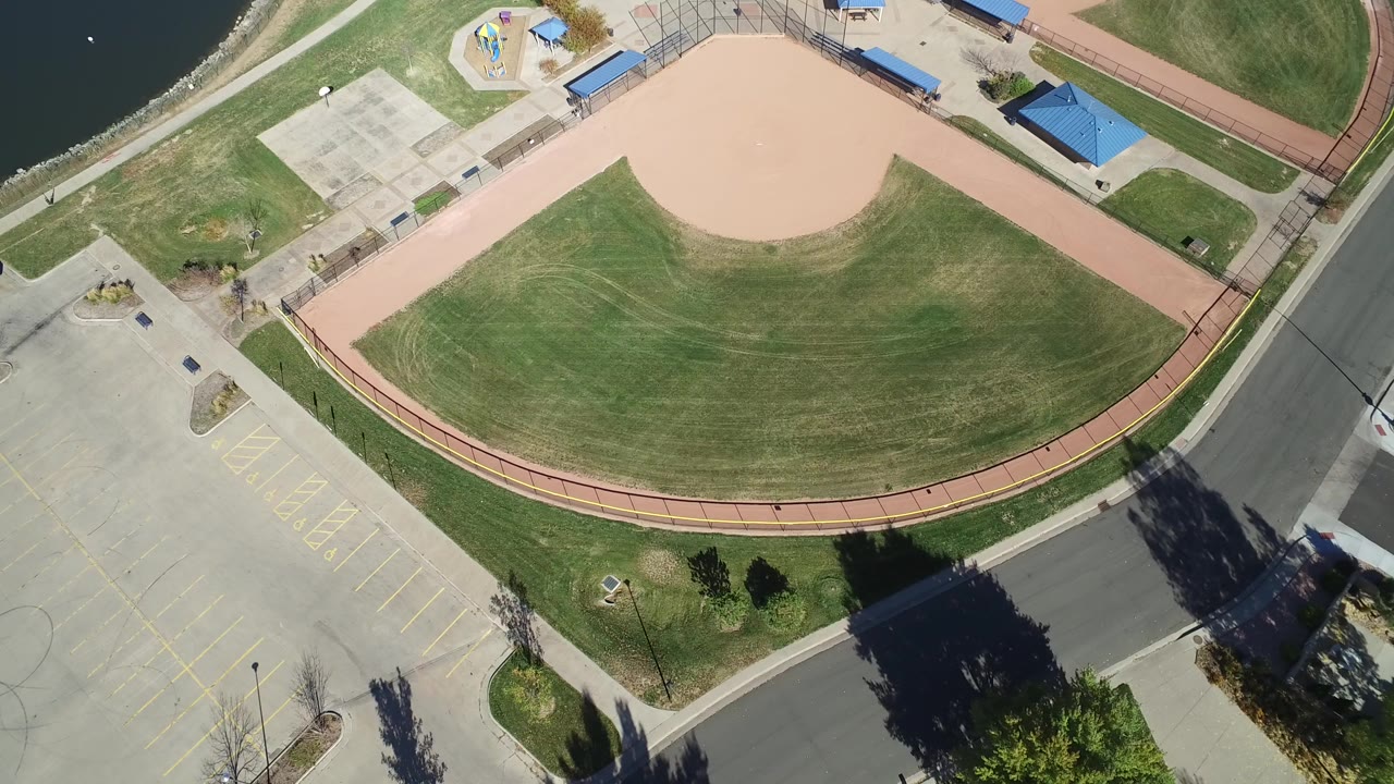 Overhead view of a large green lawn beside a parking lot and road.