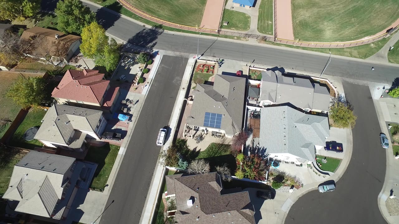 Overhead view of suburban homes beside a curved street and open grass.