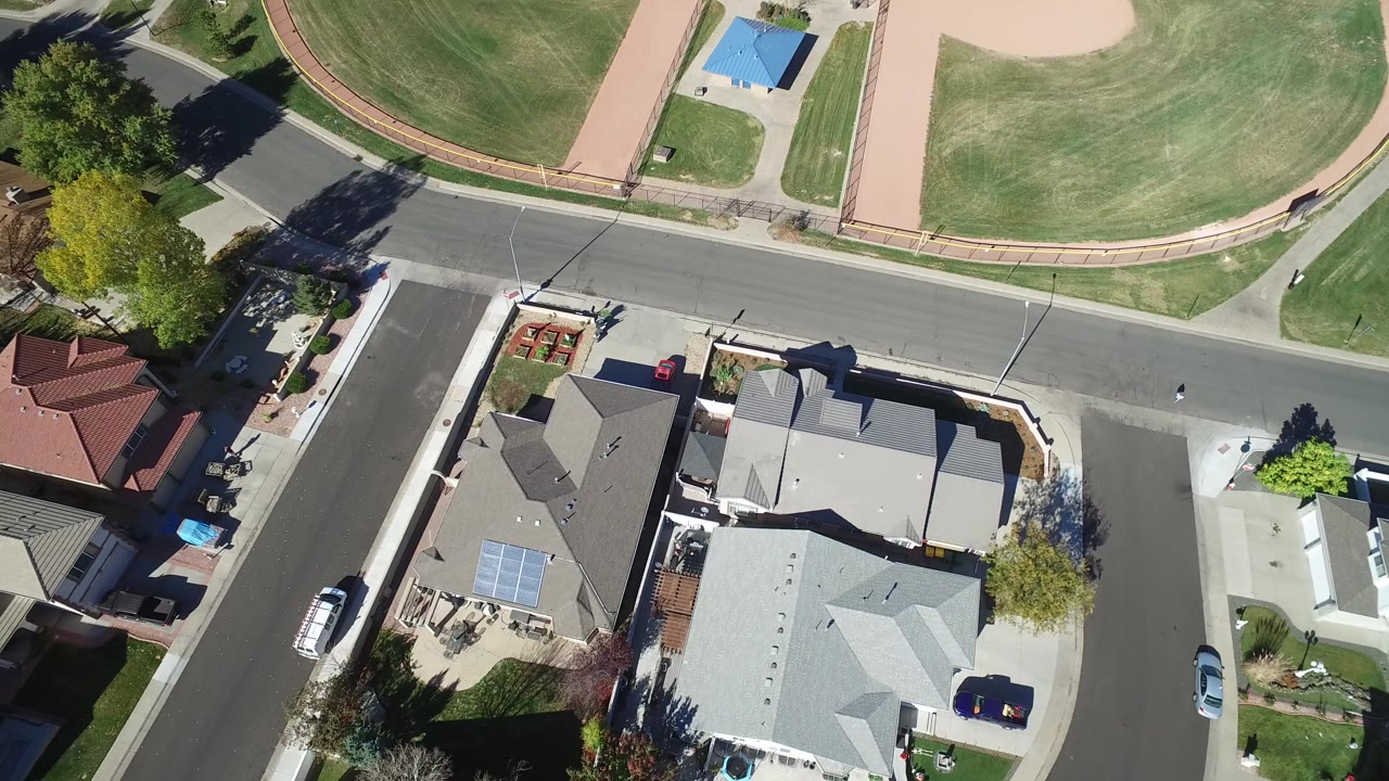 Overhead residential street beside a baseball field and houses.