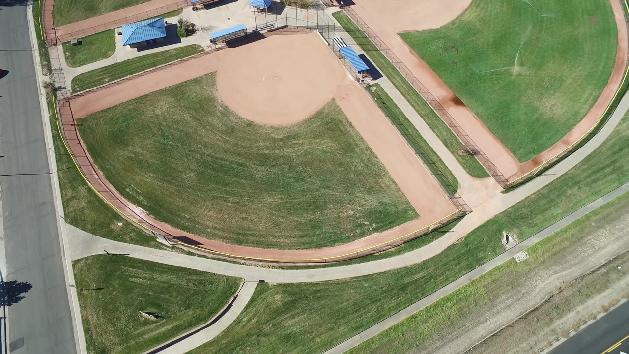 Overhead view of green ball fields and a road edge