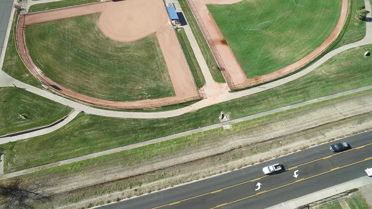 Overhead view of roadway and ballfield edges.