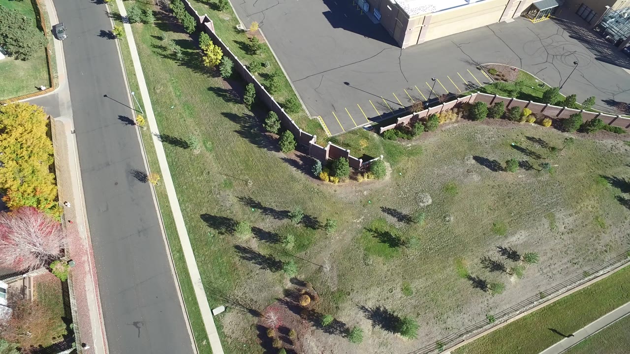 Overhead view of an empty road beside grass and a commercial parking lot.