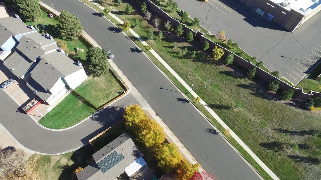 High aerial view over Hidden Lake, Colorado showing a curved residential street, detached homes, green lawns, sidewalks, and no visible people.