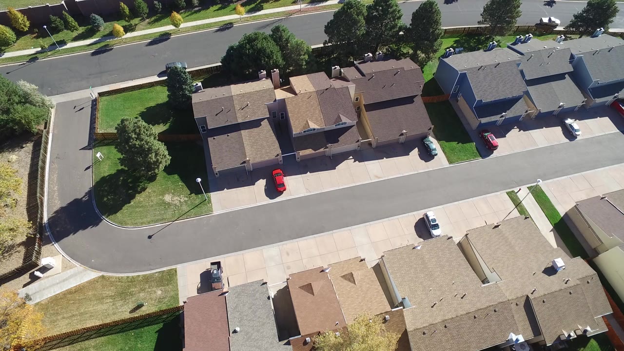 Overhead drone view of suburban houses and a curving street.