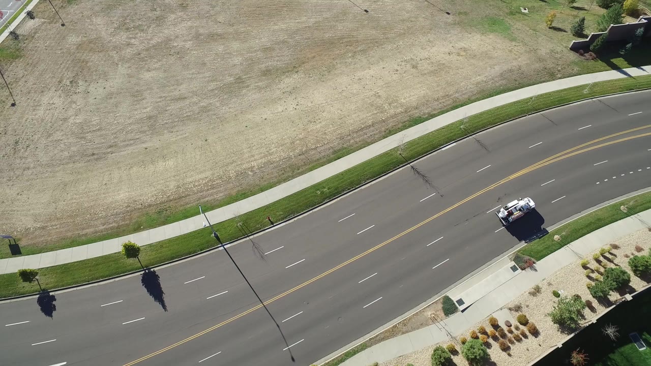 Aerial view of a curving multi-lane road beside dry grass and sidewalks.