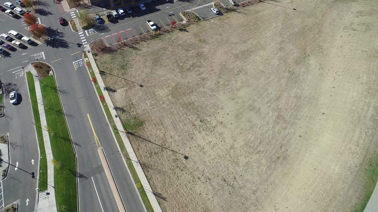 Overhead view of a road, parking lot, and pale sandy open area.