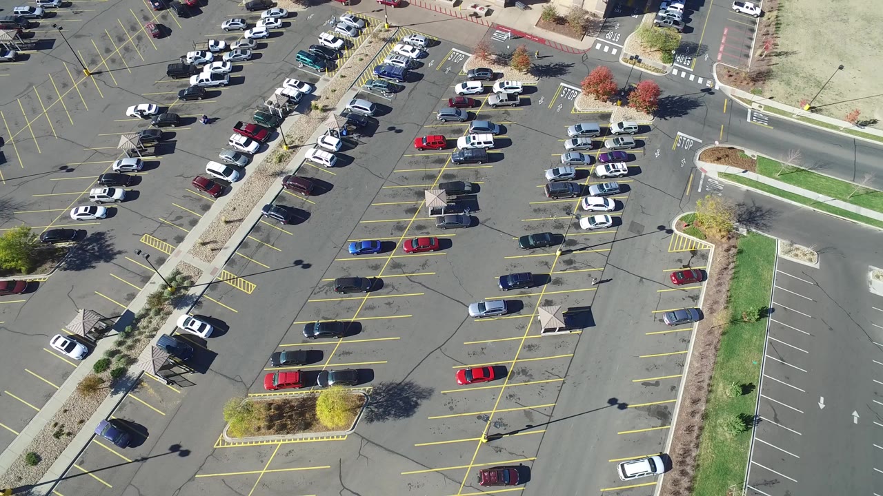 Aerial view of a large parking lot with cars and yellow stall lines.