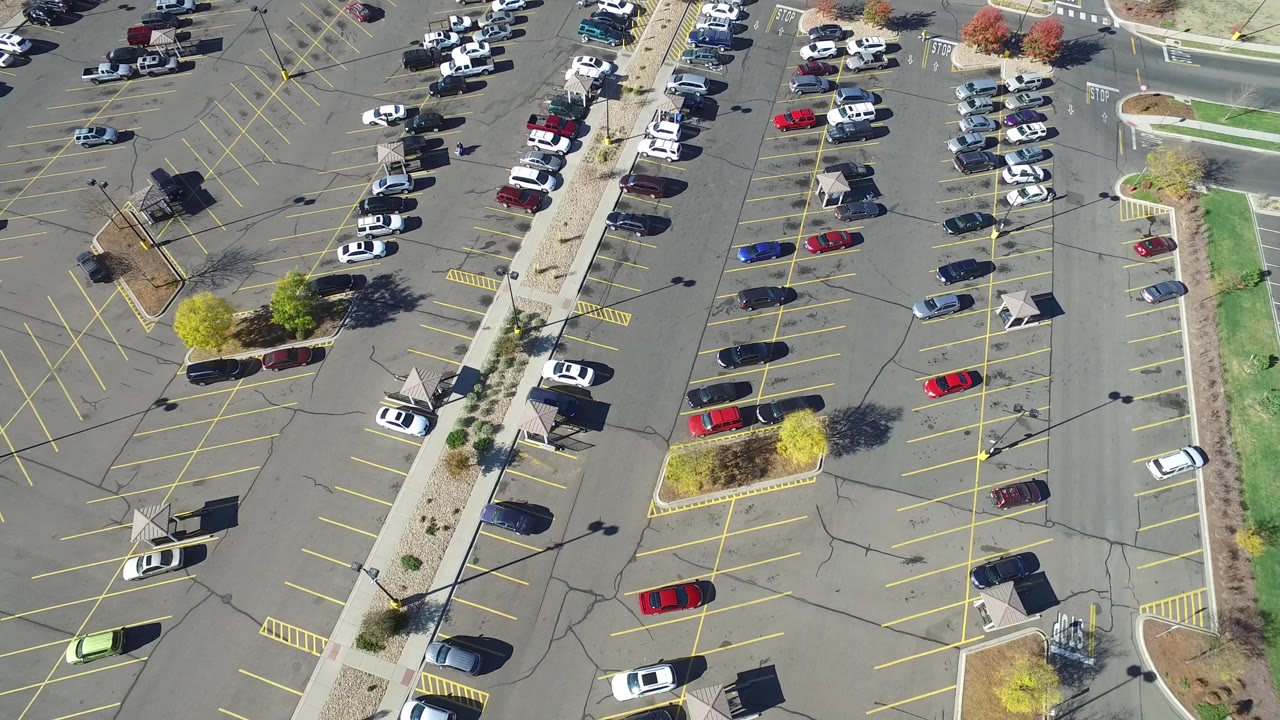 Aerial view in Hidden Lake, Colorado showing the central pedestrian strip cutting through marked parking rows, with scattered vehicles and no visible people.