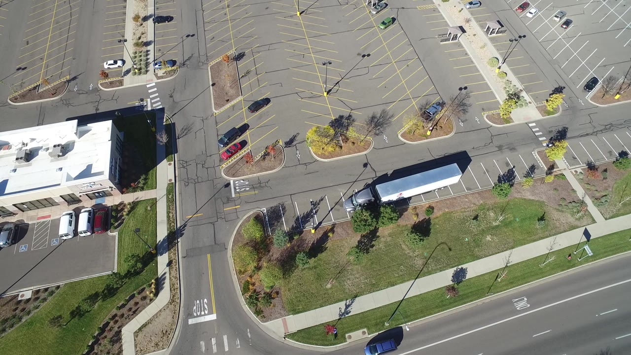 Top-down view of a car moving past a parking lot entrance.