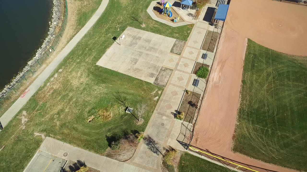 Overhead view of lakeside grass, concrete plaza, baseball infield, and playground