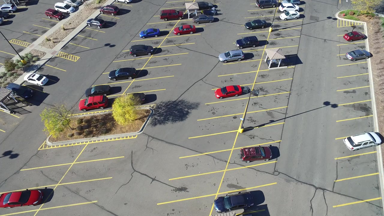 Overhead parking lot with yellow lines and scattered cars