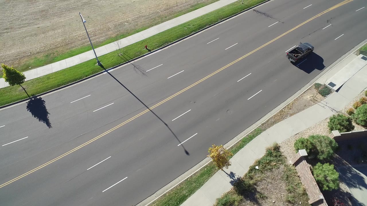 Overhead road view with a dark vehicle near the upper right