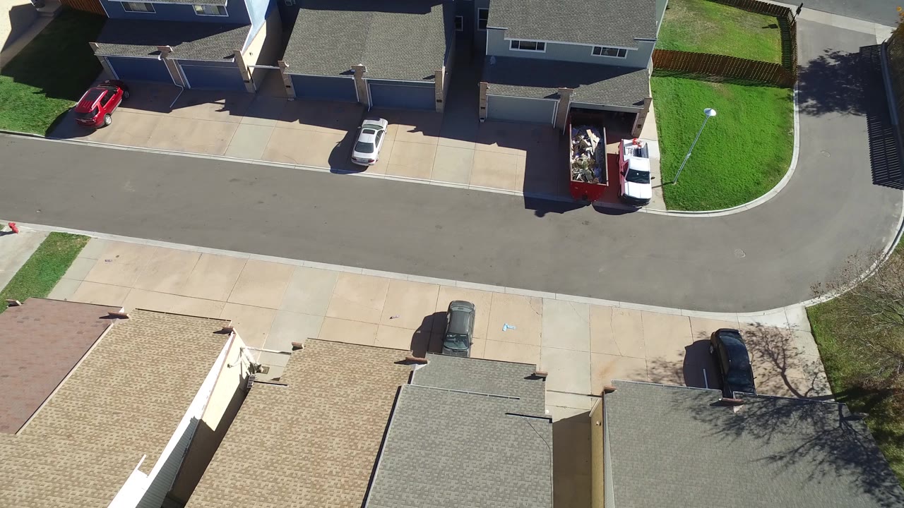 Hidden Lake, Colorado aerial frame with the street running across the center, a white car in a driveway, a red container or trailer near a house, and no clearly recognizable people.