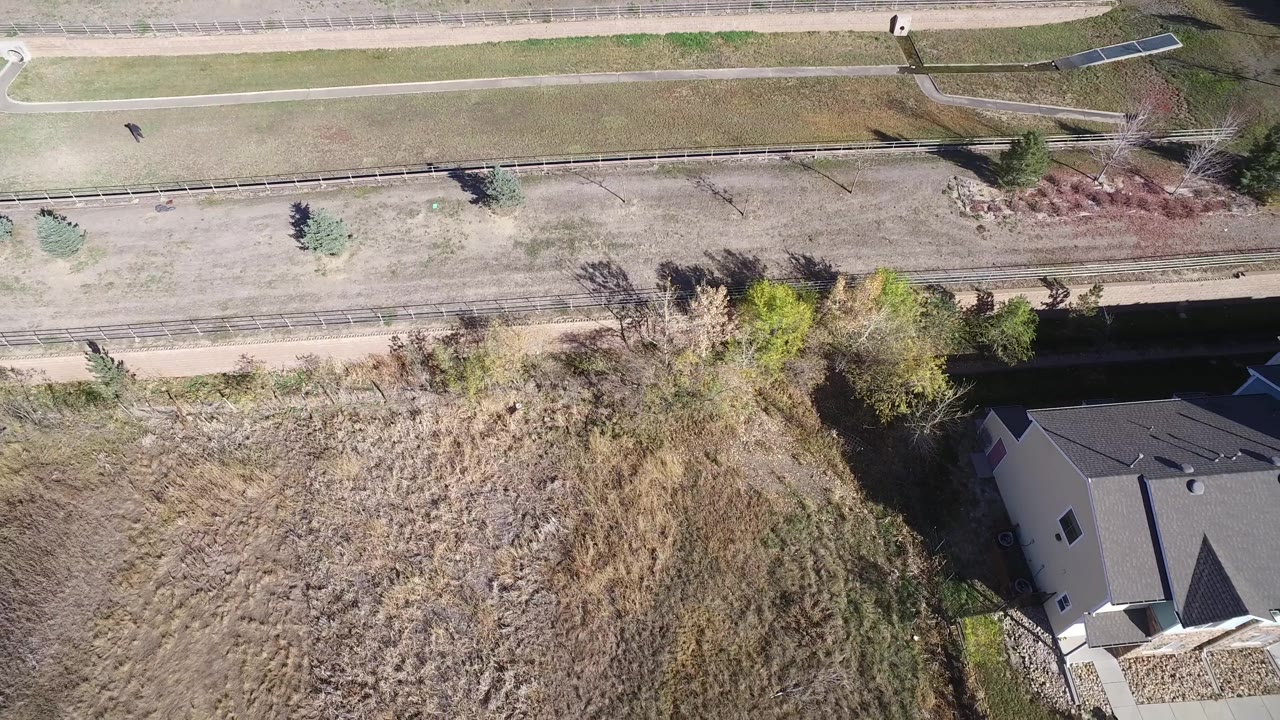 Drone view of open lot next to attached homes and paths