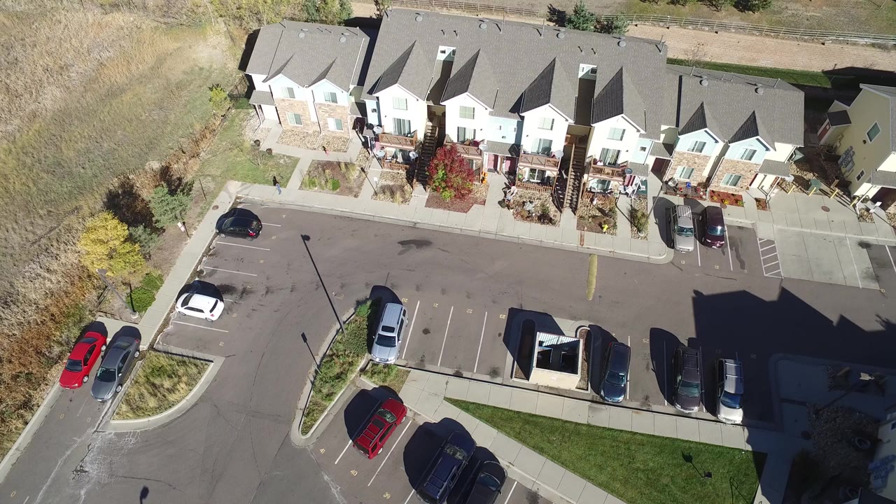 Overhead view of townhomes, parked cars, and a suburban parking area.