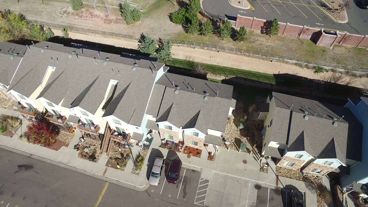 Overhead frame of gray-roofed apartment buildings in Hidden Lake, Colorado, with driveways, parked cars, a landscaped strip, and no visible people.