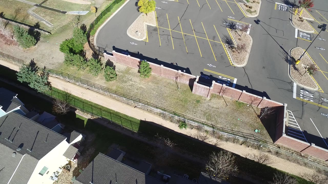 At 0:01, the aerial frame in Hidden Lake, Colorado centers more of the empty parking bays, landscaped islands, curbs, asphalt, and no visible people.