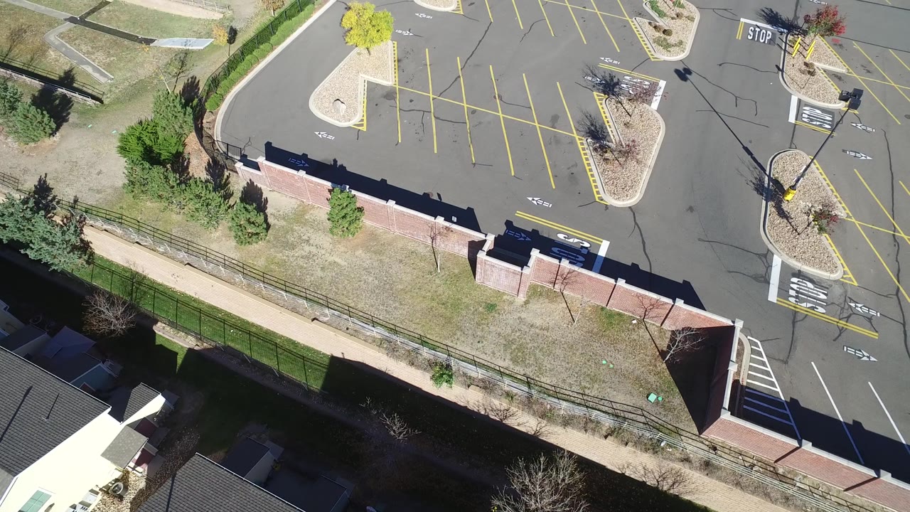 Top-down parking lot view with stop markings, islands, wall, and grass.