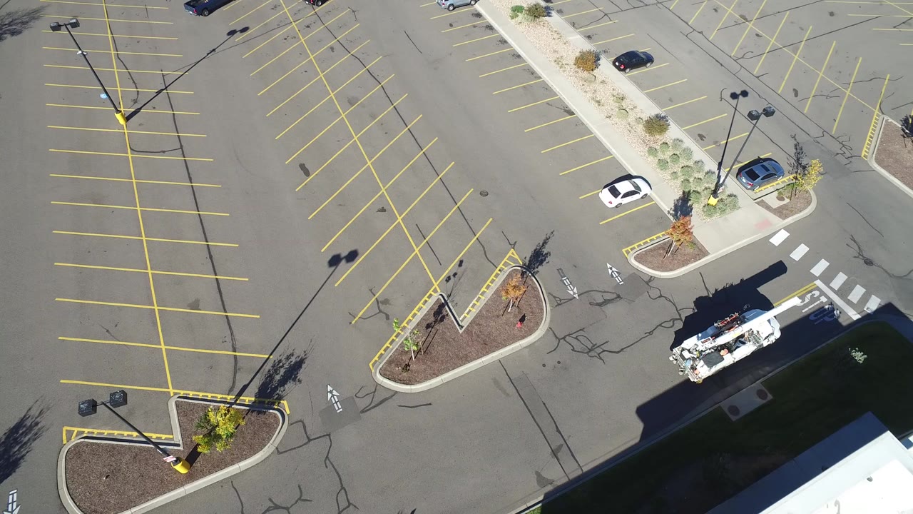 Overhead view of a white utility truck in an empty parking lot.