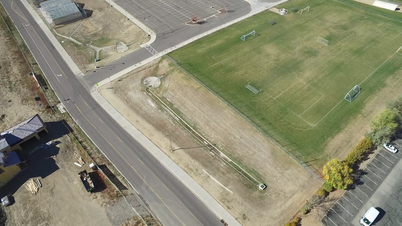 Overhead view of a sports field beside a paved road and parking areas.