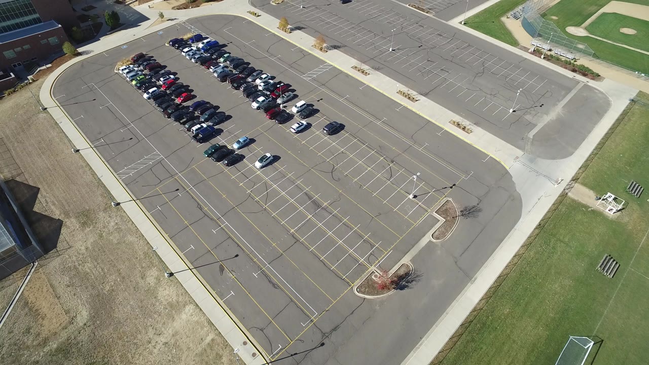 Overhead parking lot with rows of cars and empty spaces