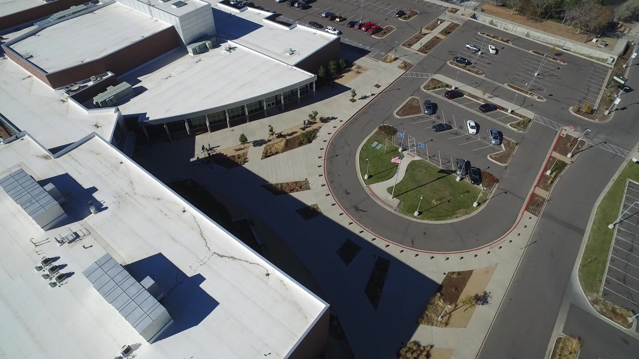 Aerial view of a white-roofed commercial building and parking lot.