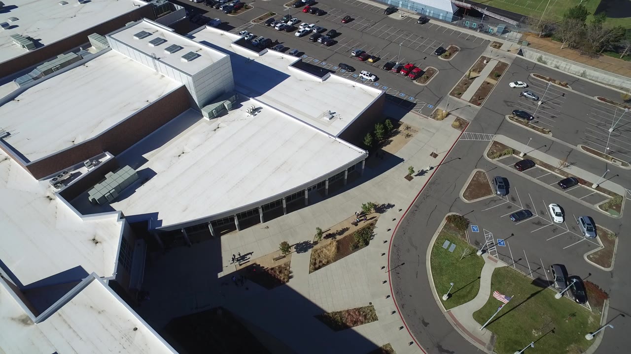 Overhead frame in Hidden Lake, Colorado showing white flat roofs, gray asphalt lots, scattered parked cars, curving access lanes, and no visible people.