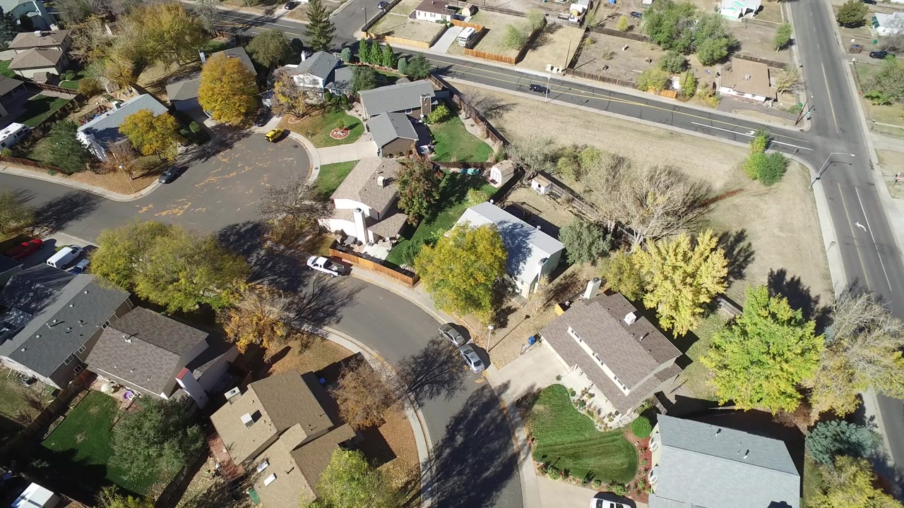 Overhead view of a cul-de-sac, homes, trees, lawns, and parked cars.