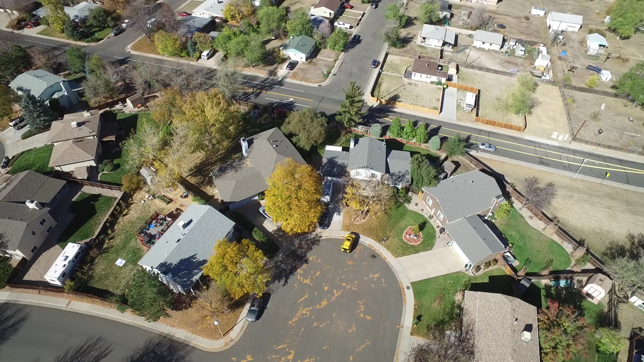 Drone-style view of suburban houses beside a road and cul-de-sac.