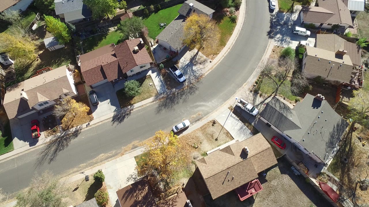 Overhead view of a curving residential road and detached homes.
